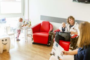 Wartezimmer mit Kindern und sich unterhaltenden Erwachsenen