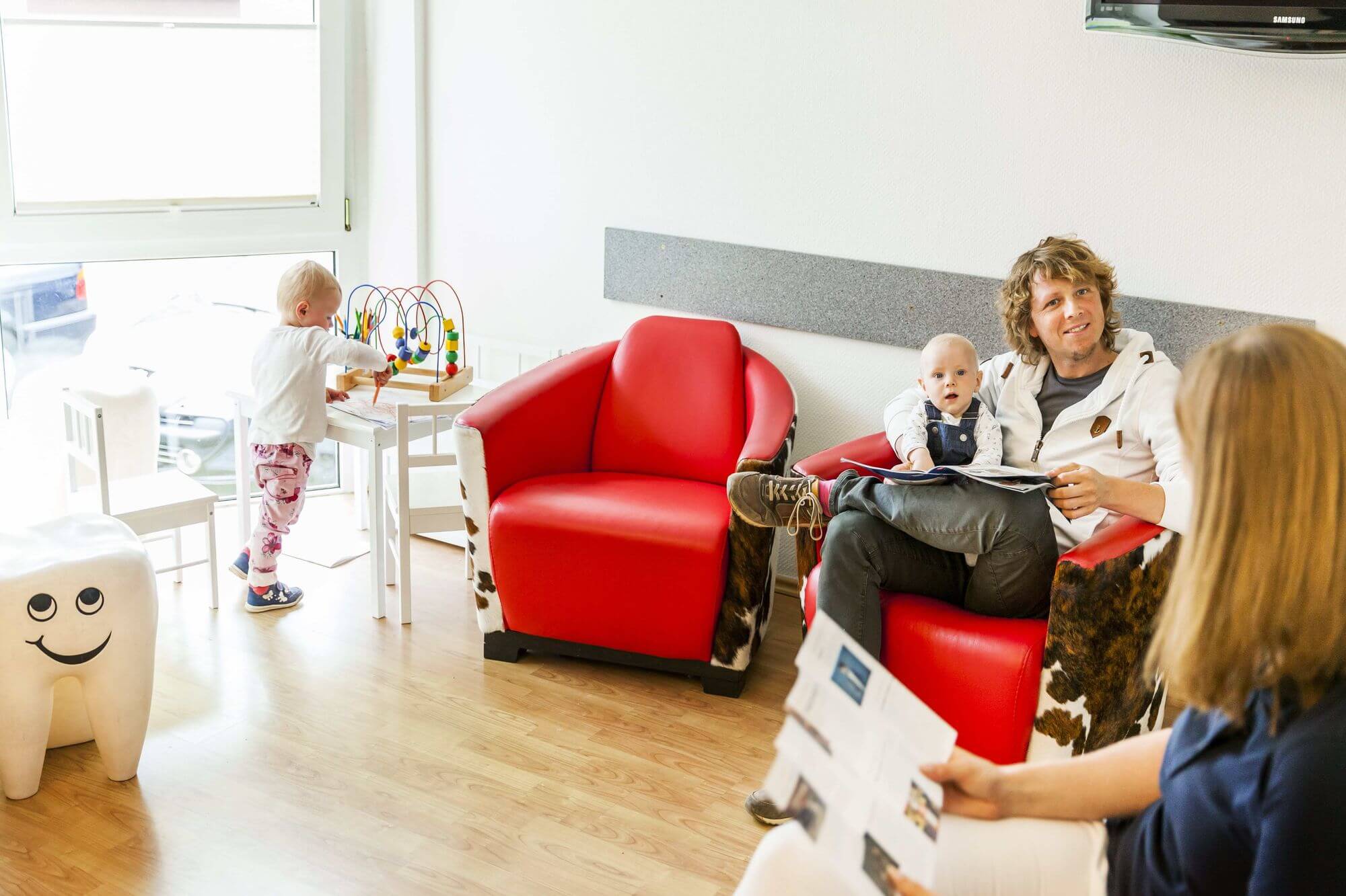 Wartezimmer mit Kindern und sich unterhaltenden Erwachsenen