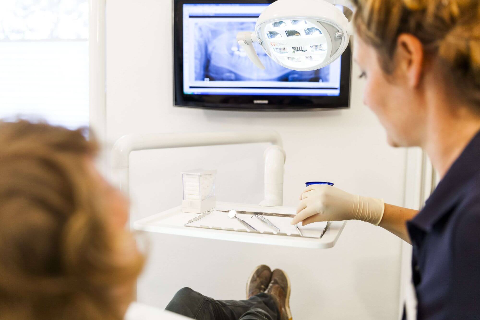 Zahnärztin beginnt mit Behandlung eines Patienten