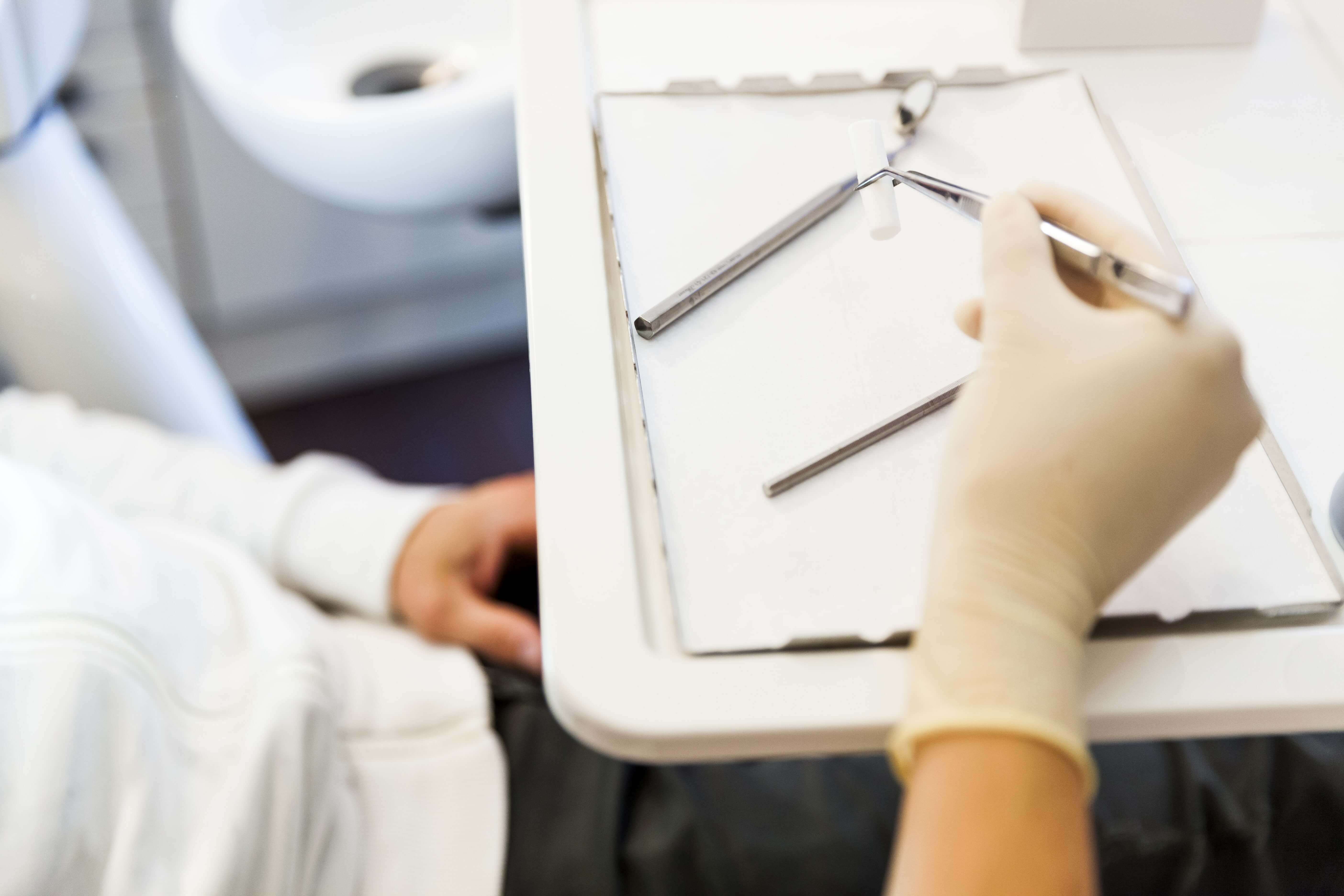 Hand hält zahnmedizinisches Instrument am Behandlungsstuhl