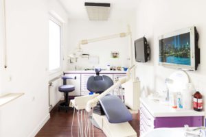 Behandlungszimmer mit Stühlen und Schränken mit violetter Farbnote